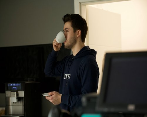 person drinking coffee and looking away from screen