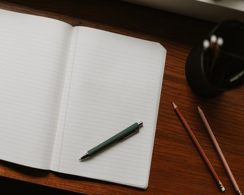 open notebook with pen on a clean wooden desk